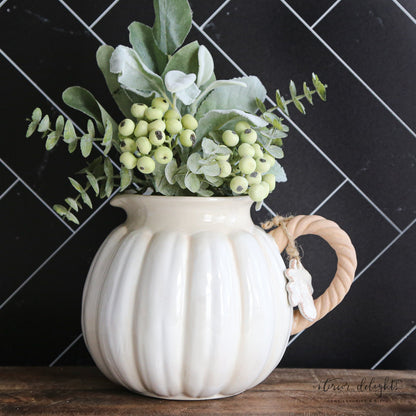 Charming white pumpkin pitcher with a twisted vine handle and leaf accent tag, perfect for fall decorating.